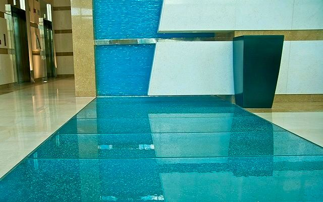 Blue-tiled indoor walkway with a curved wall and a white-and-teal bench-like structure.