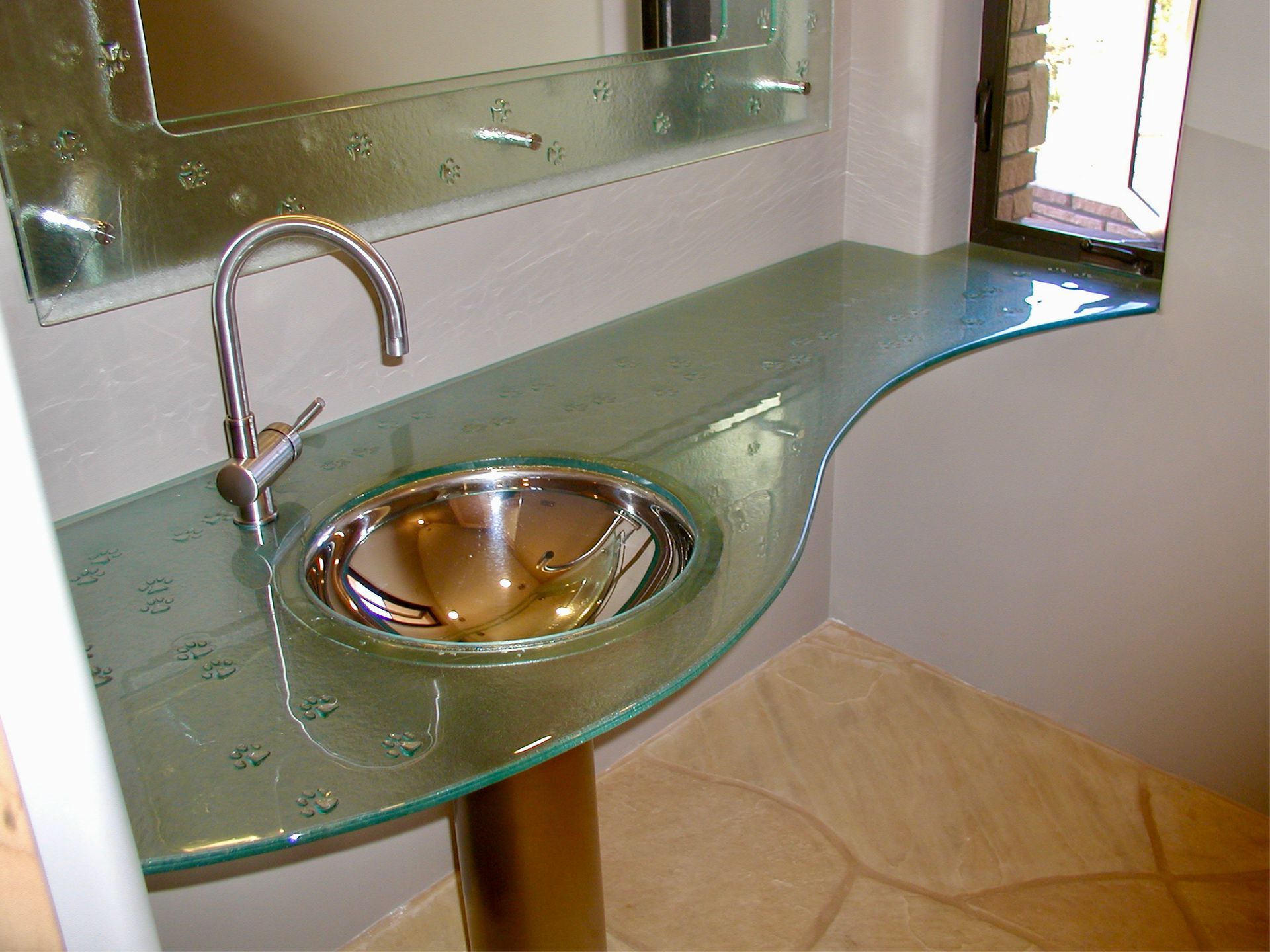 Modern glass bathroom sink with chrome faucet and green countertop near a mirror