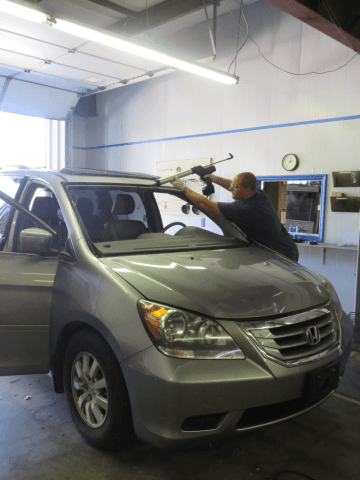 A man is working on a car windshield in a garage.