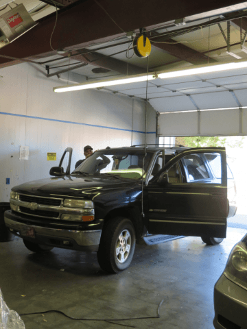 A black suv is parked in a garage with its doors open