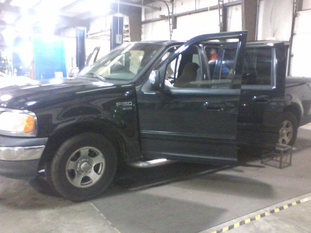 A black truck is parked in a garage with its doors open