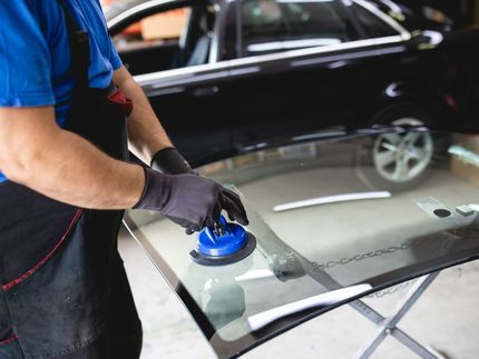 A man is installing a windshield on a car.