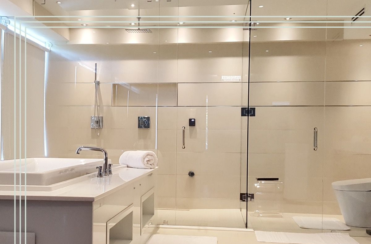 Modern bathroom with glass shower, white fixtures, and beige walls.