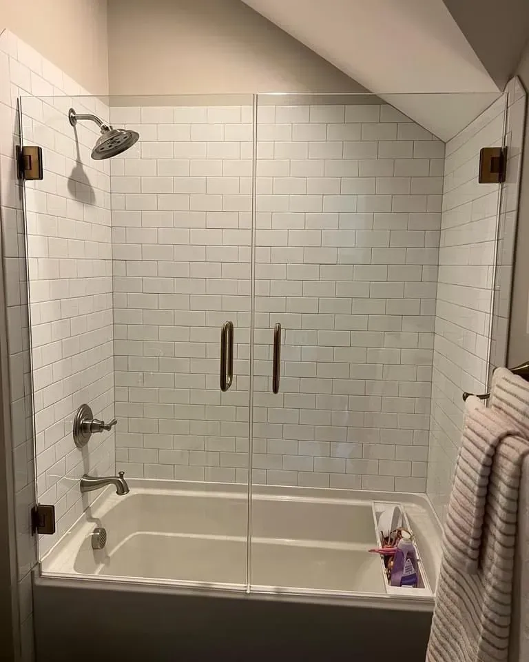 A bathroom with a bathtub and a shower with a glass door.