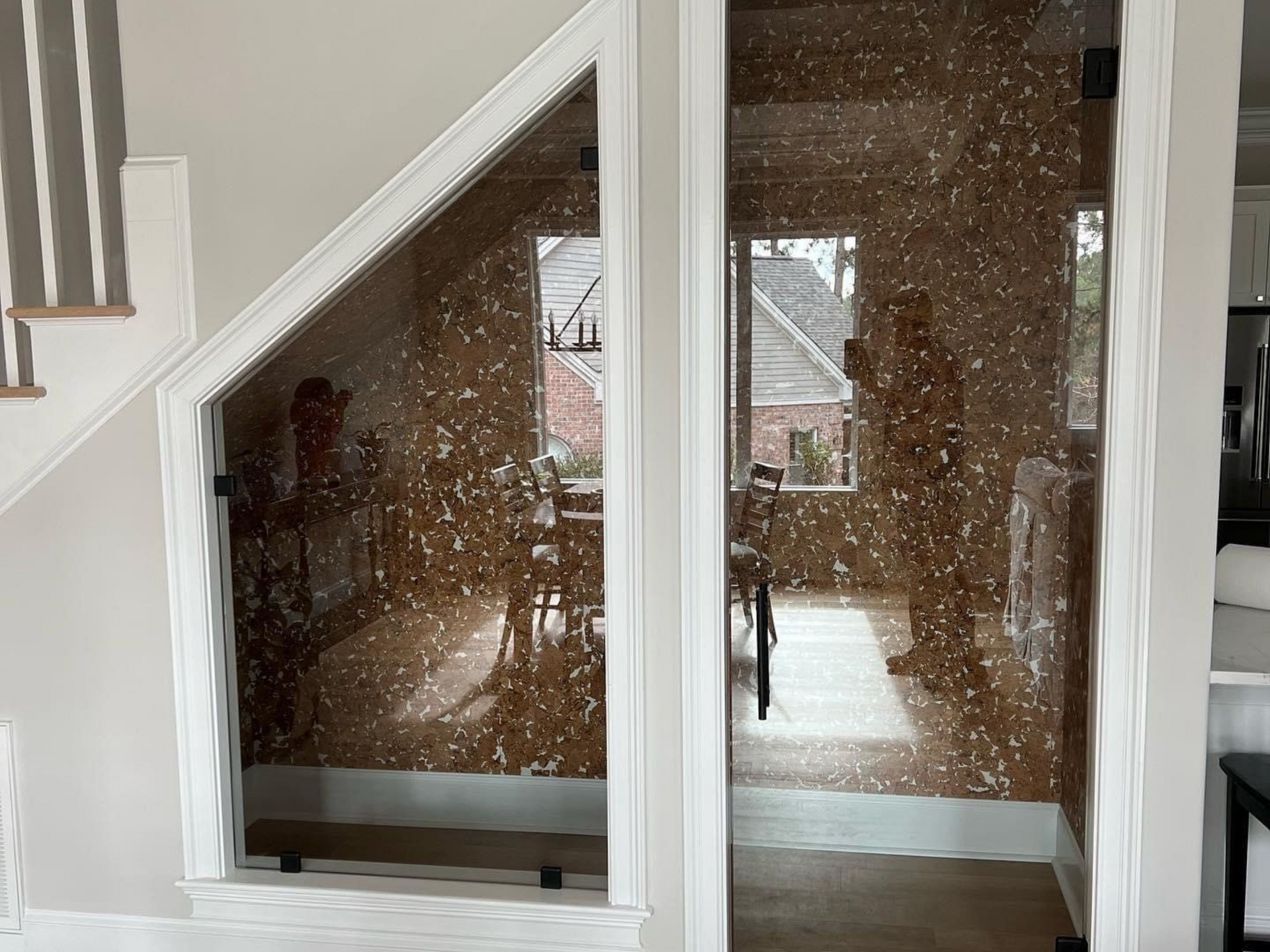 Glass panels with a decorative overlay, framing a dining area visible from a stairwell in Raeford, NC.