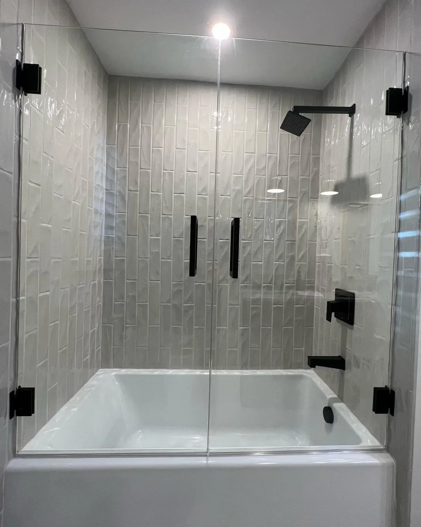 A bathroom with a bathtub and a shower with a glass door.