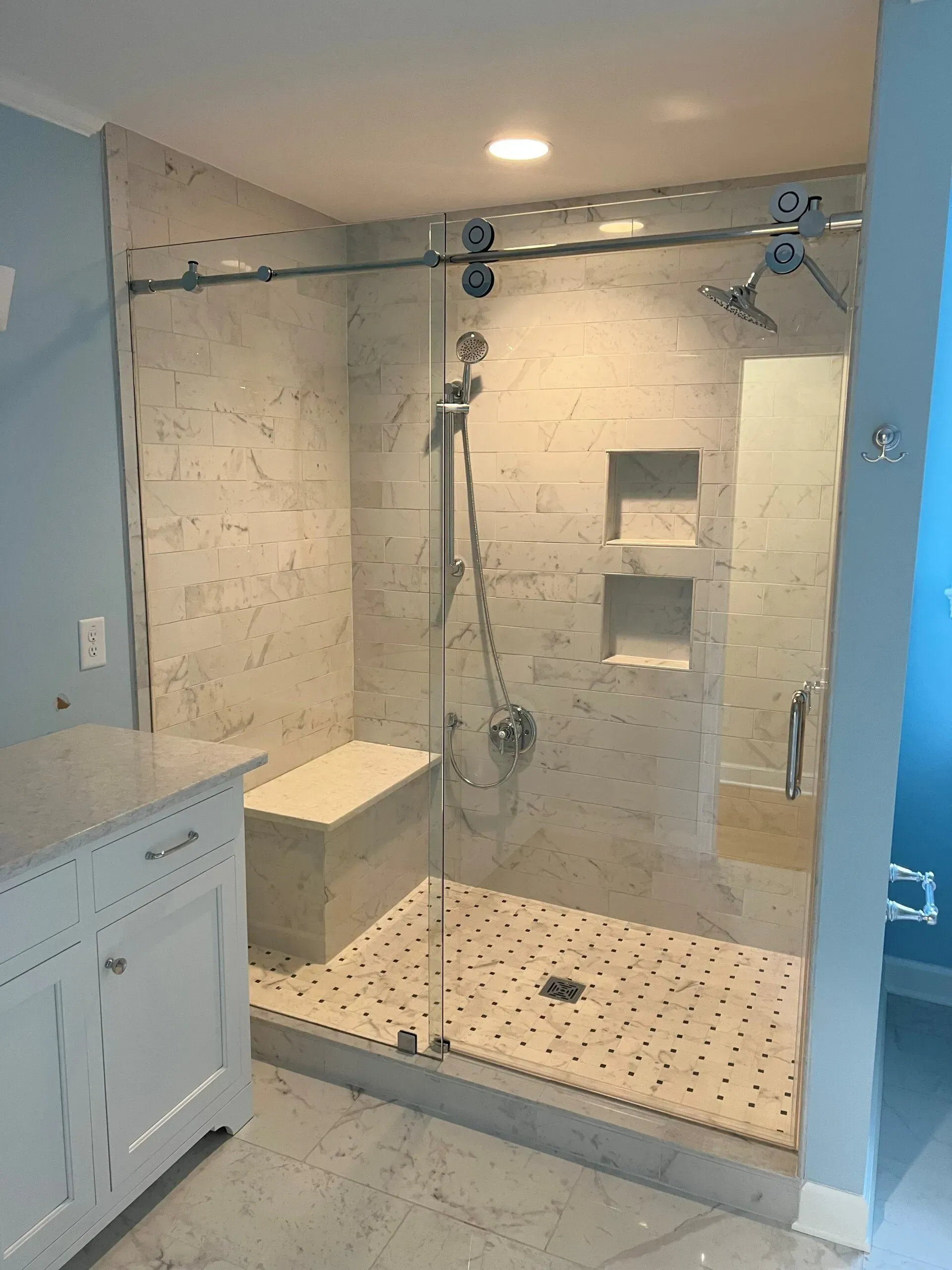 A bathroom with a walk in shower with a sliding glass door.