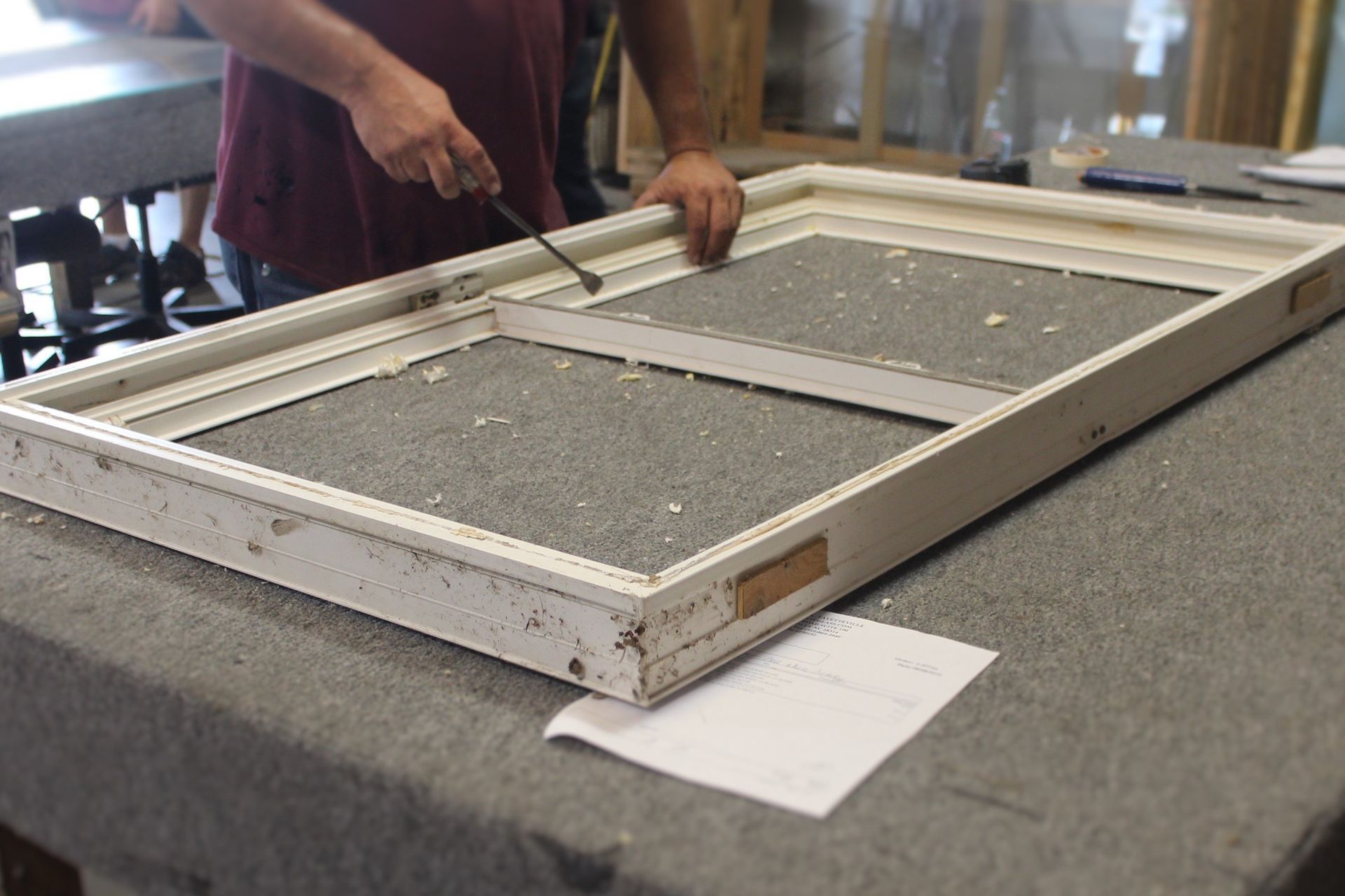 A man is working on a window frame on a table.
