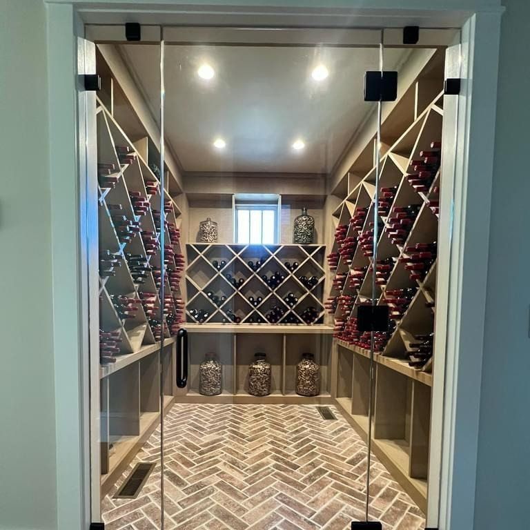 A wine cellar with a glass door and shelves filled with wine bottles.