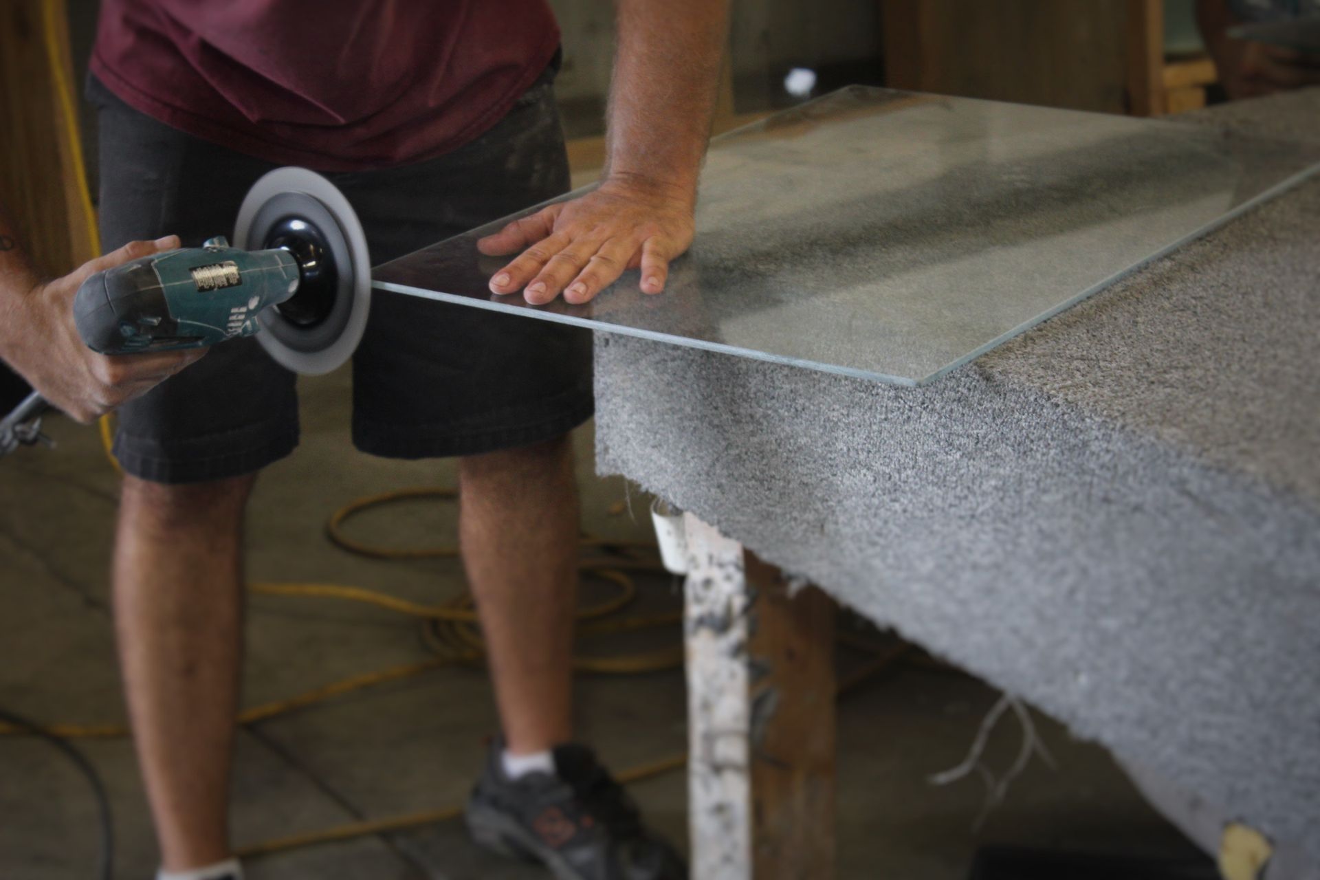 A man is polishing a piece of glass with a machine.