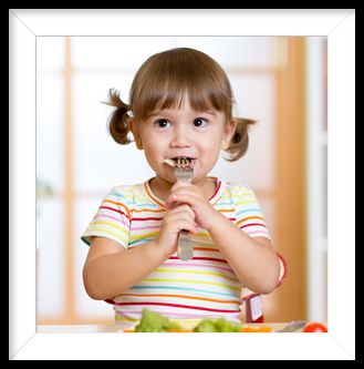 Young child enjoying a healthy nursery lunch provided by Cupcakes Catering