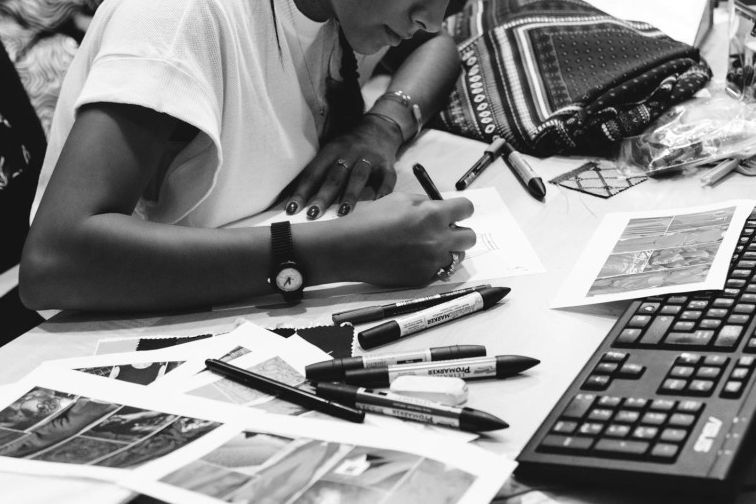 Una persona è seduta a una scrivania con una tastiera e delle penne