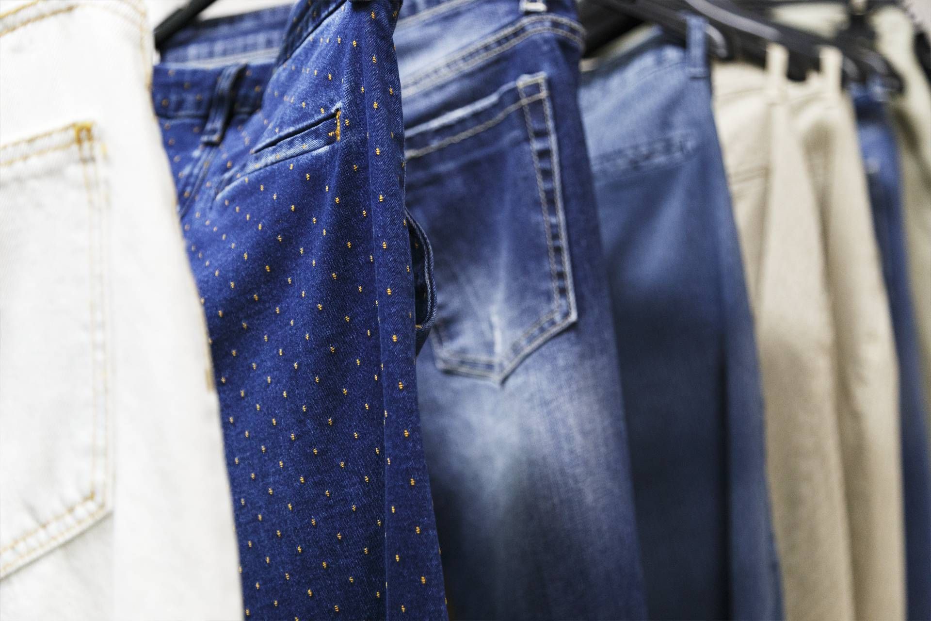 Una fila di jeans appesi su uno scaffale in un negozio.