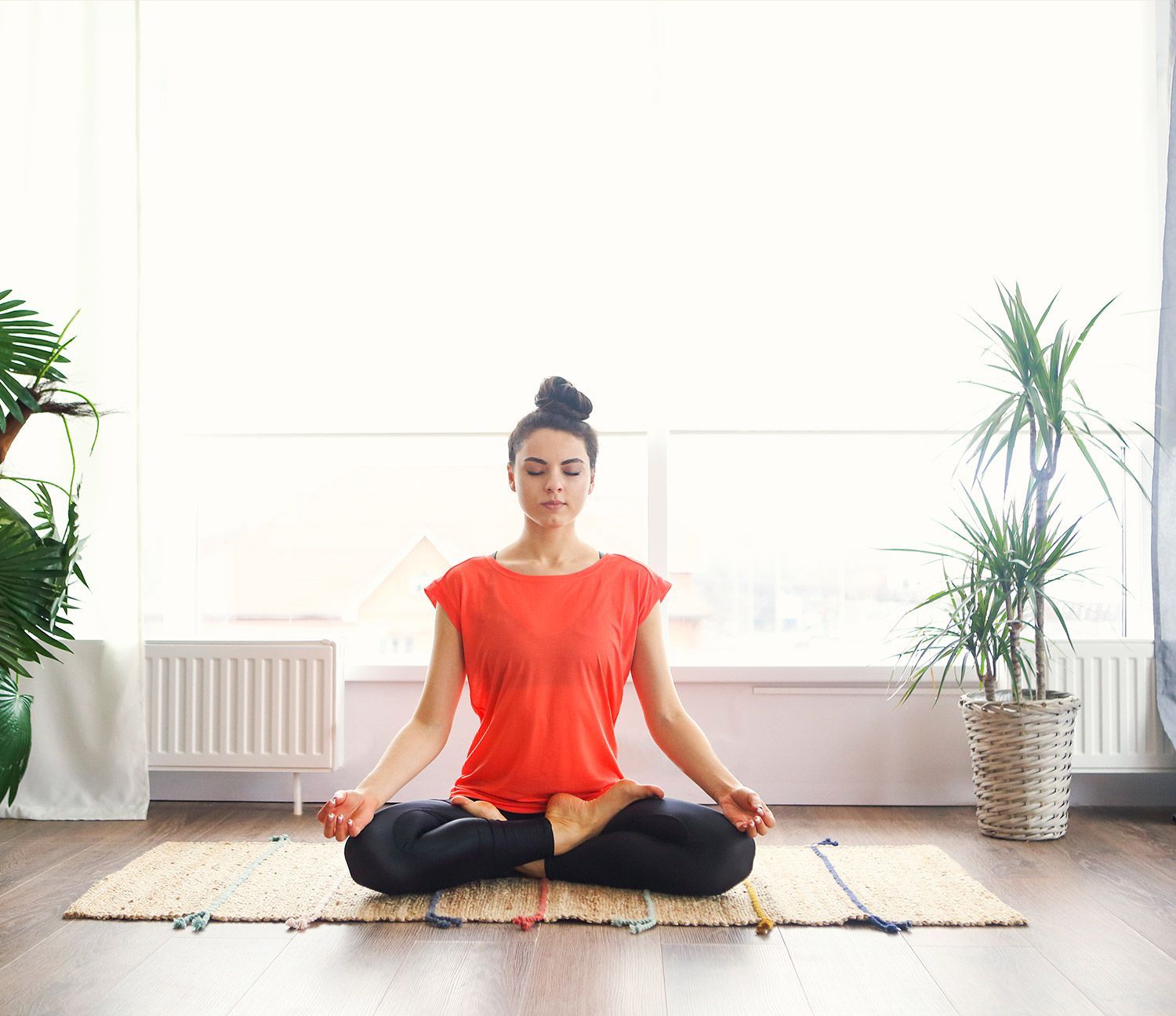 Woman Sitting in a Lotus Position on a Yoga Mat Woman Sitting in a Lotus Position on a Yoga Mat