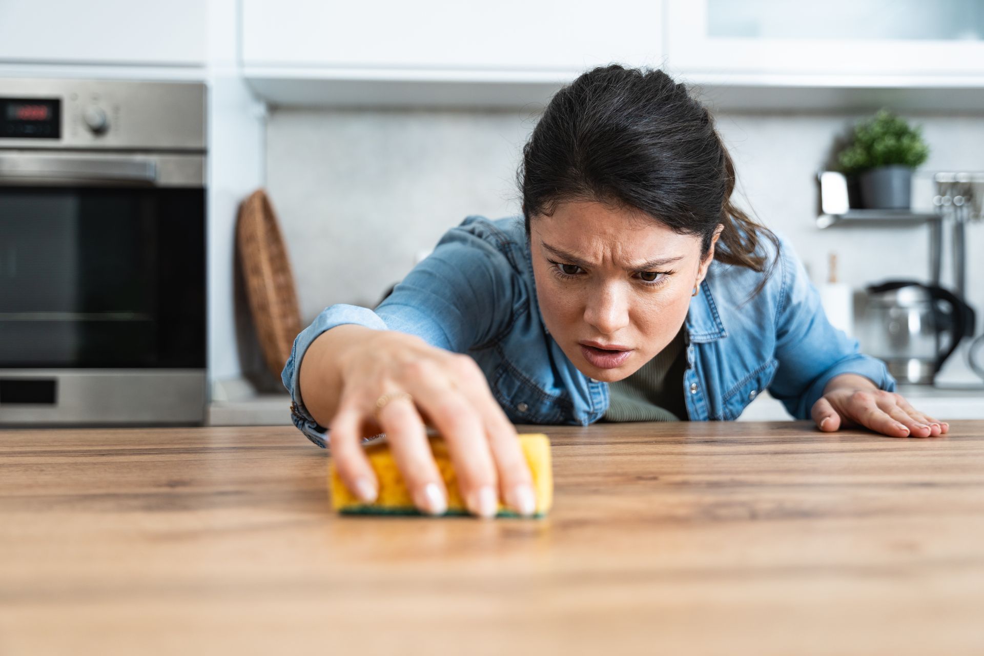 Woman intensely cleaning kitchen counter with a sponge.