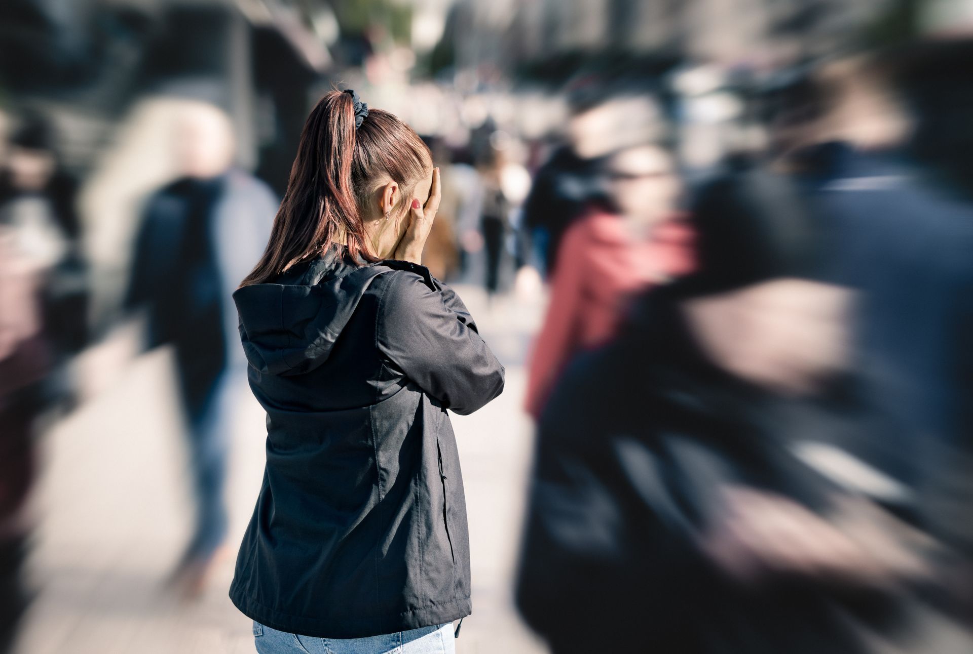 Woman covers face, overwhelmed by a blurry crowd on a city street. Woman covers face, overwhelmed by a blurry crowd on a city street.