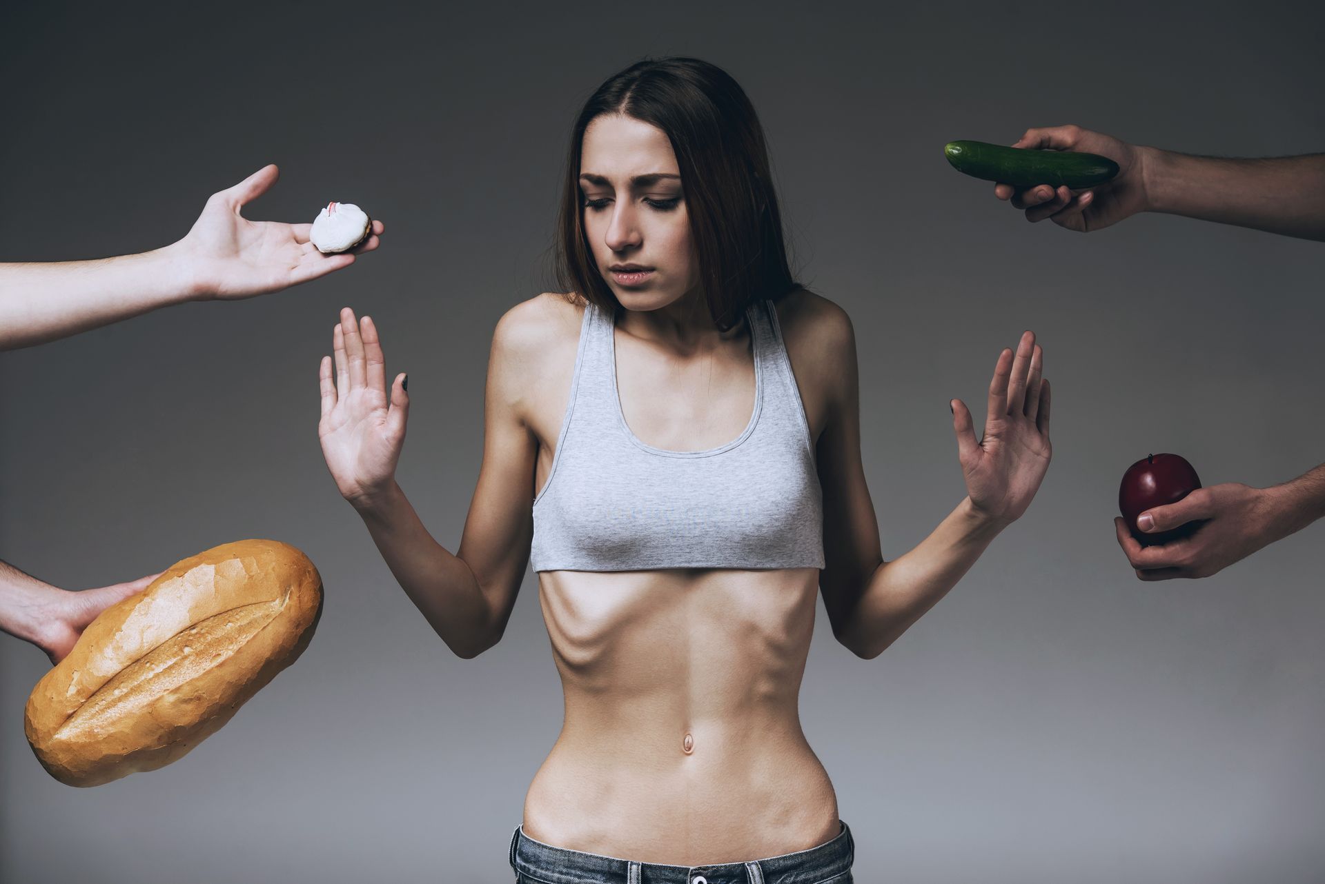 Underweight person with hands outstretched, rejecting food: bread, pills, cucumber, and apple.