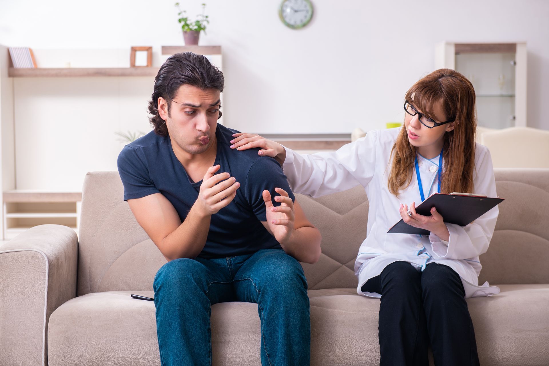 Person on couch being consoled by a person in a lab coat, holding clipboard.