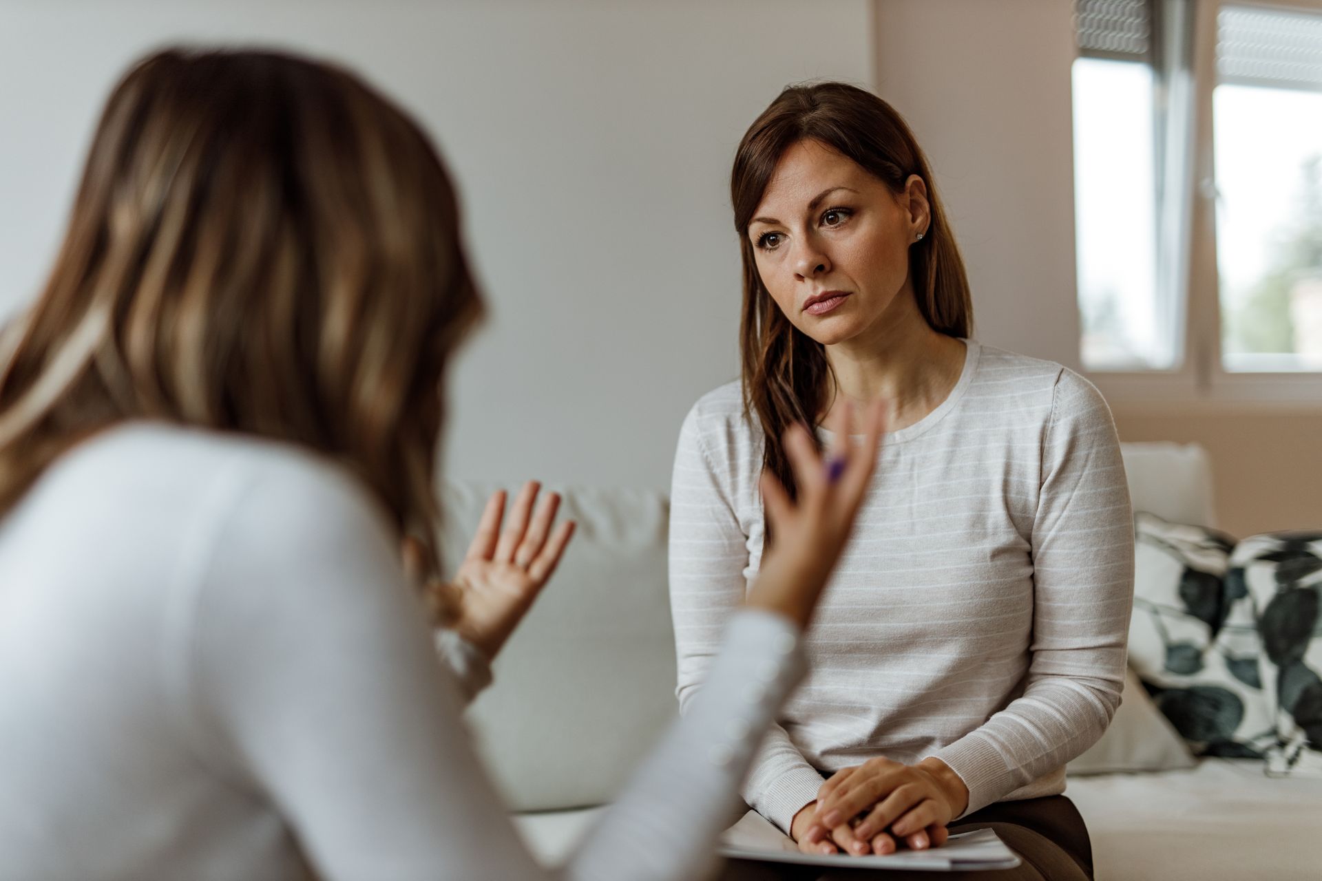 Woman listening to another woman gesturing; soft, natural light, indoors. Woman listening to another woman gesturing; soft, natural light, indoors.