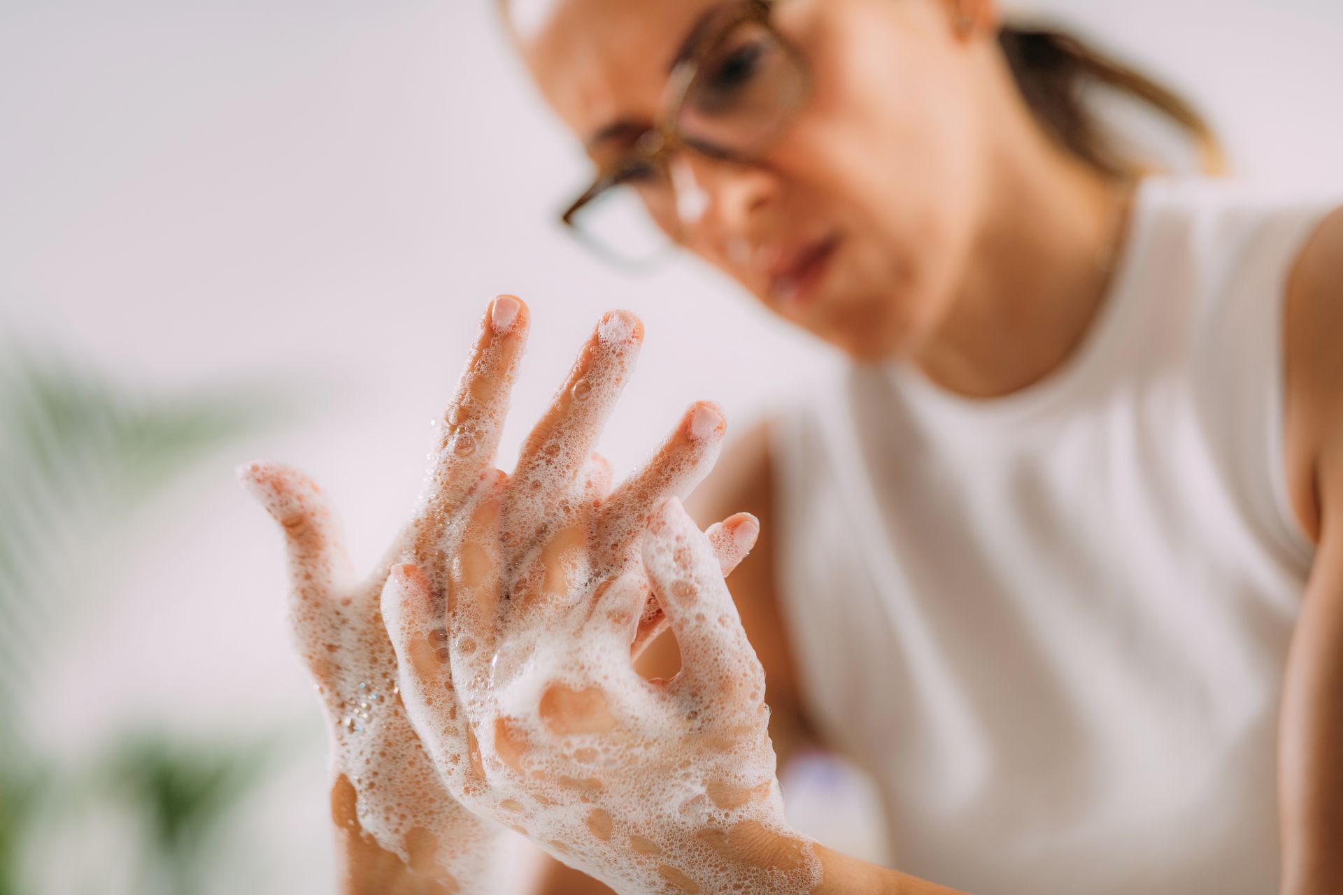 Woman intensely washing hands with soap, hands covered in foam.