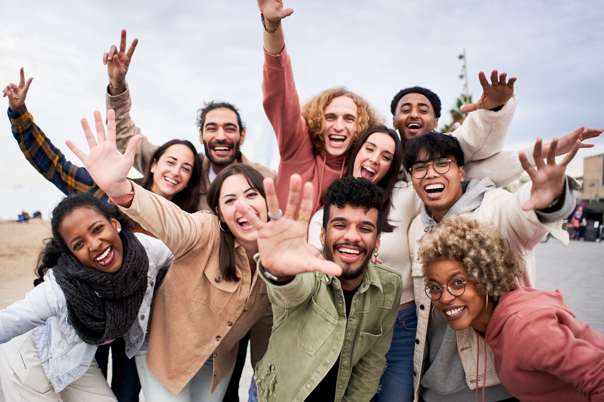 Group of young people smiling and waving outdoors.