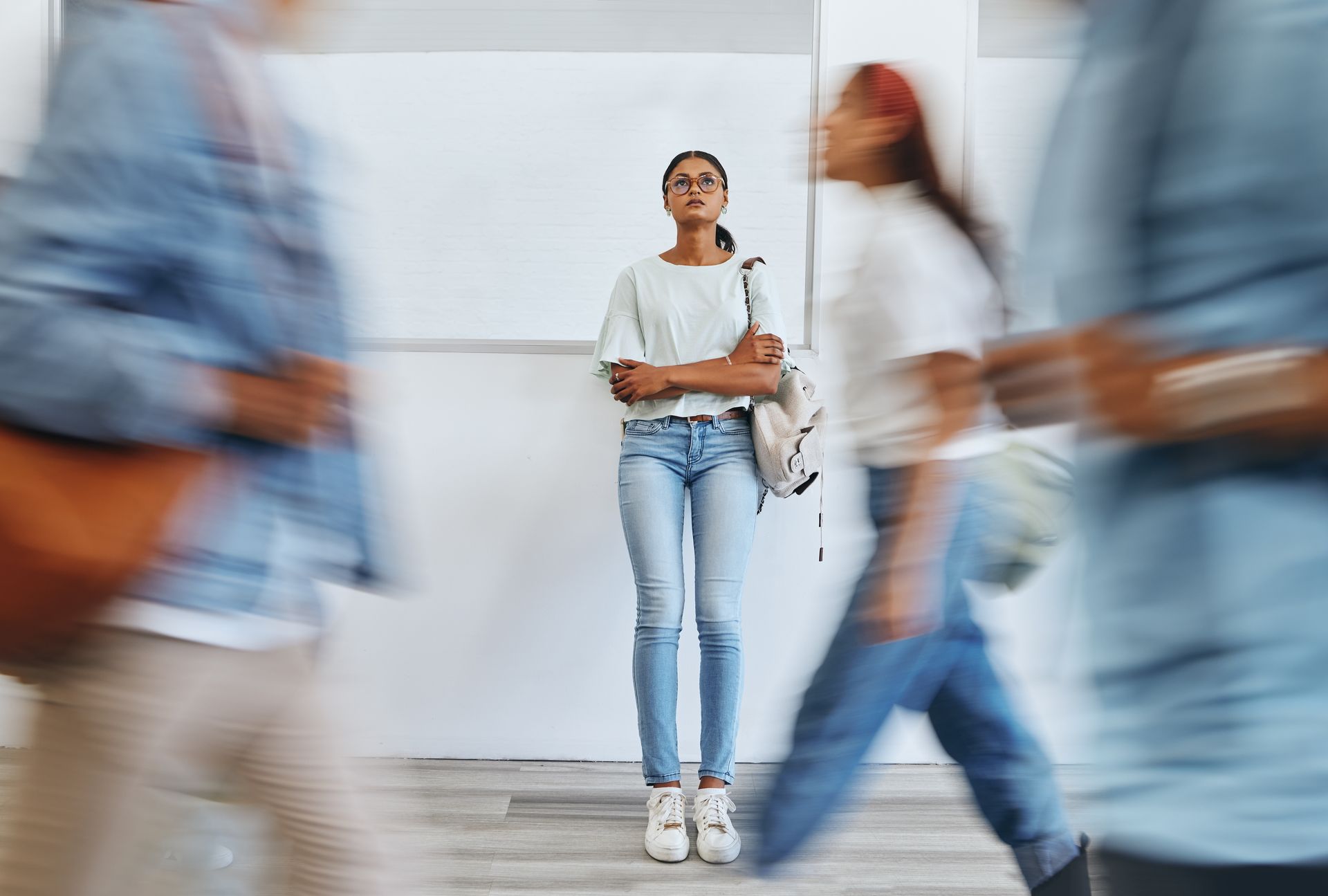 Woman standing in hallway with arms crossed, surrounded by blurred people walking. Woman standing in hallway with arms crossed, surrounded by blurred people walking.
