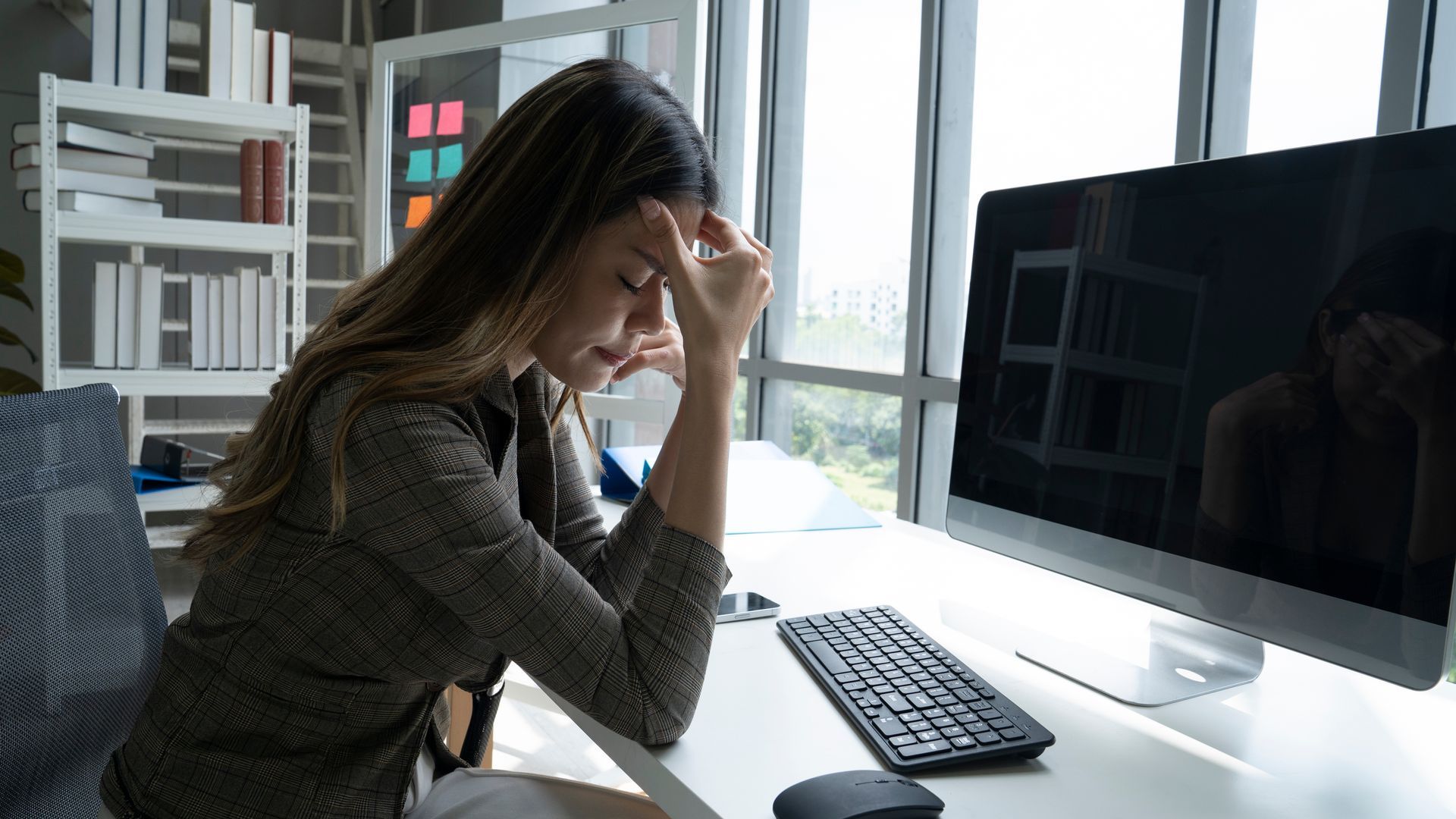 Woman at desk with head in hand, looking stressed near computer. Woman at desk with head in hand, looking stressed near computer.