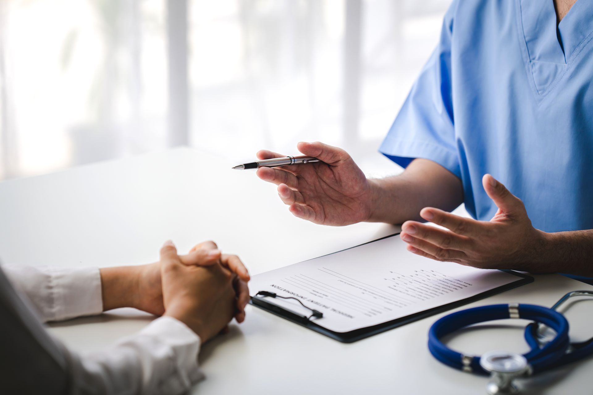 Doctor discussing paperwork with a patient, stethoscope on table. Doctor discussing paperwork with a patient, stethoscope on table.