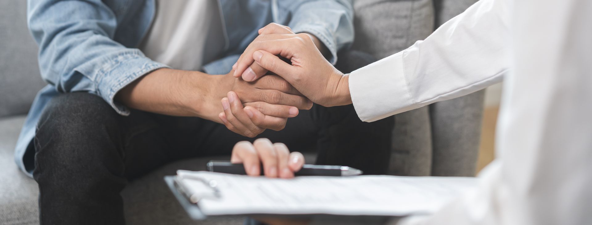 Two people holding hands, one wearing a denim jacket, the other a white coat, a clipboard in front. Two people holding hands, one wearing a denim jacket, the other a white coat, a clipboard in front.
