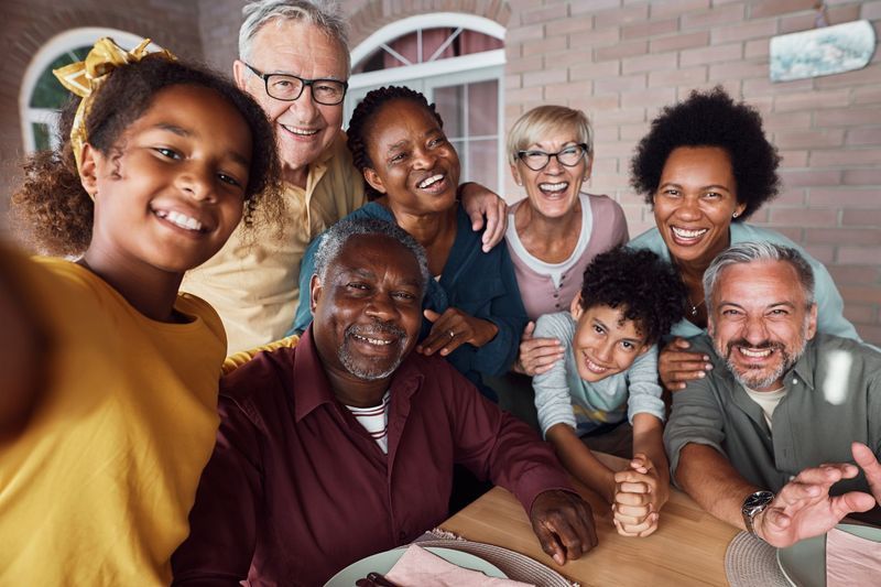 Family smiles for a selfie on a brick patio.