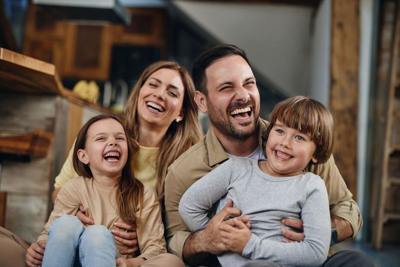 Family of four, smiling and laughing together indoors.
