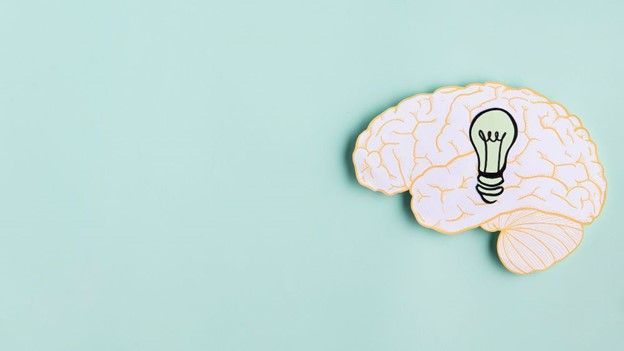 Brain with a lightbulb in it on a blue-green background.