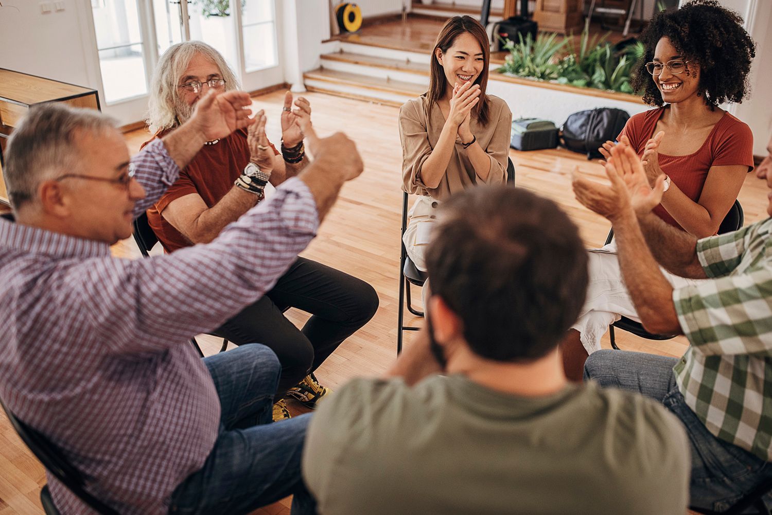 A group of people are sitting in a circle clapping their hands.