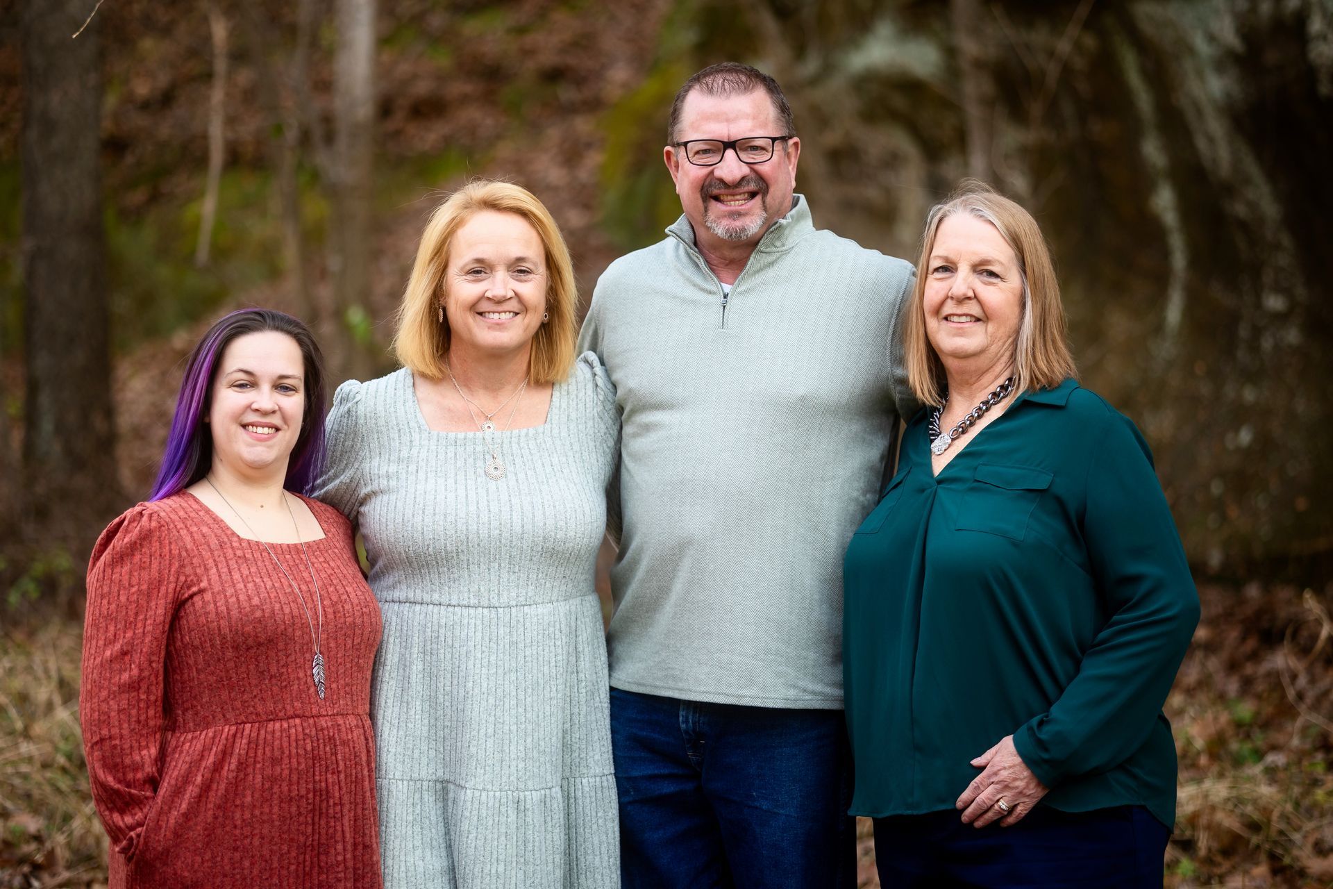 Four people pose together outdoors; two women, a man, another woman smile.