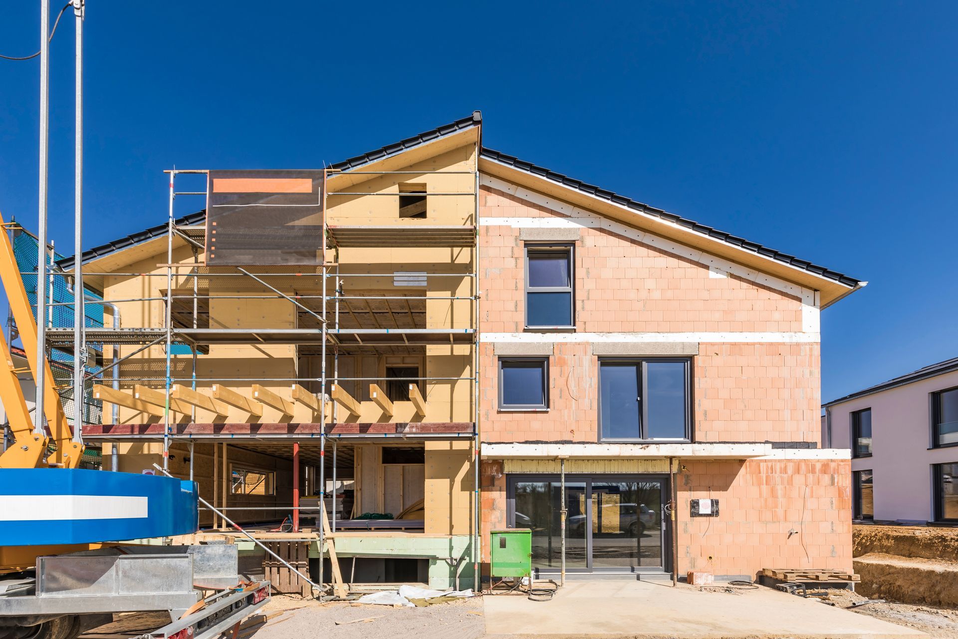 Construction of a multi-story building with a crane against a blue sky.