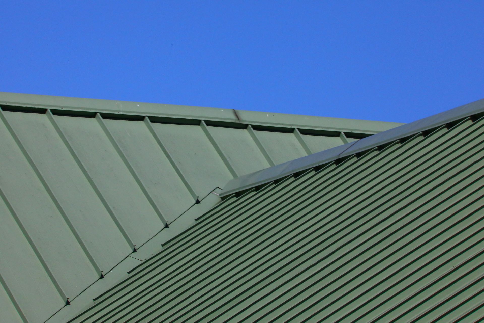 Green metal roof panels against a blue sky.