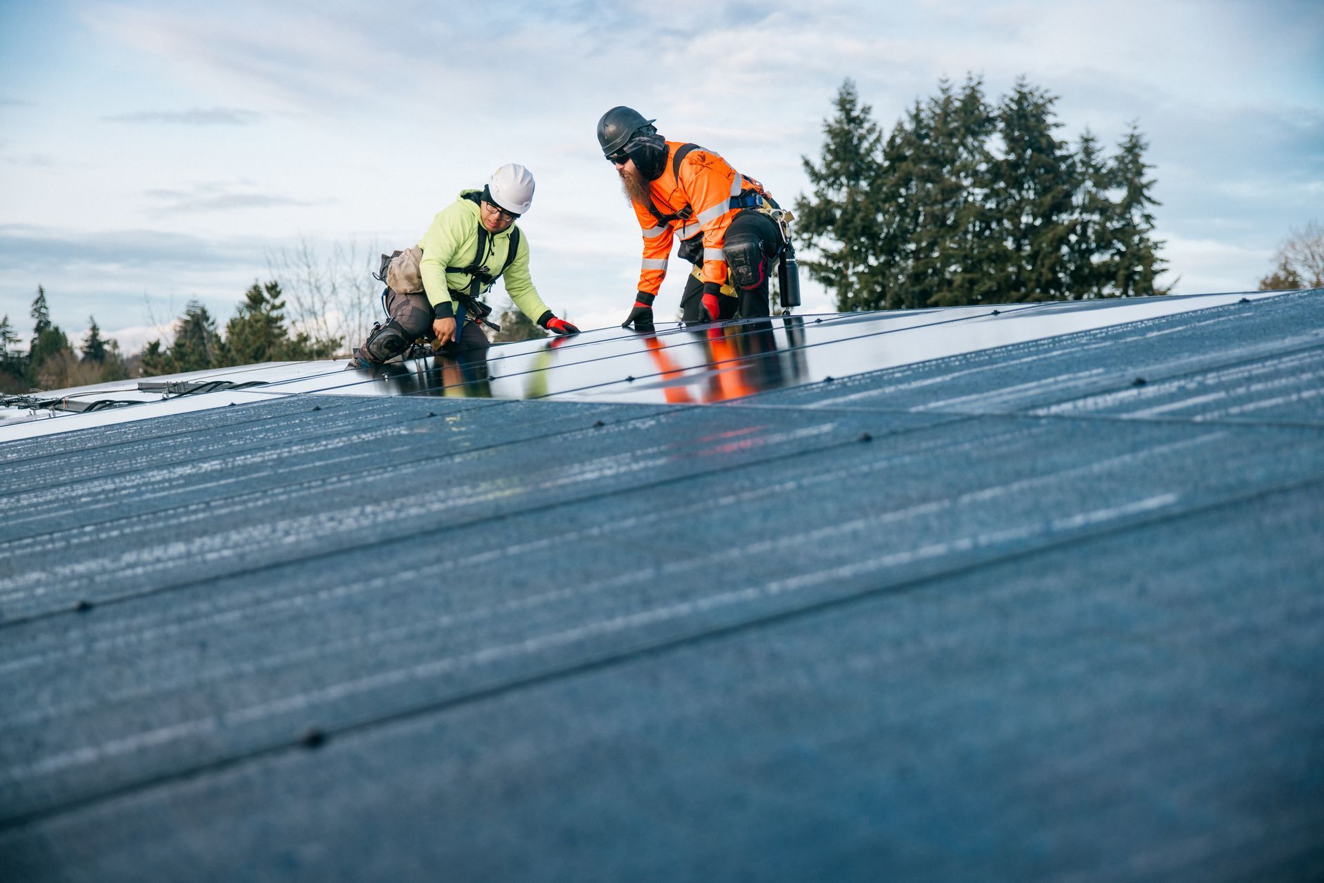 Technicians work on solar panel installation in housing development.