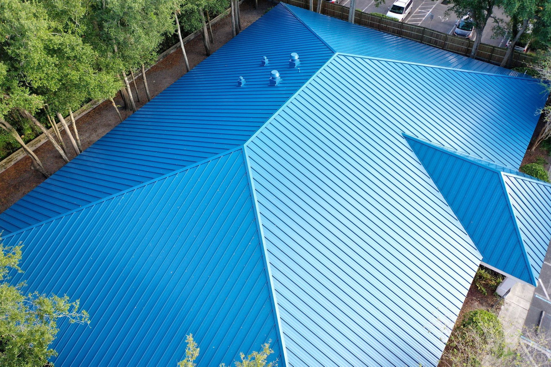 Dark metal roof with skylights and chimney against a blue and pink sky.