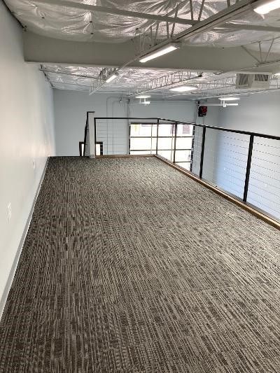 An empty room with a carpeted floor and a balcony.