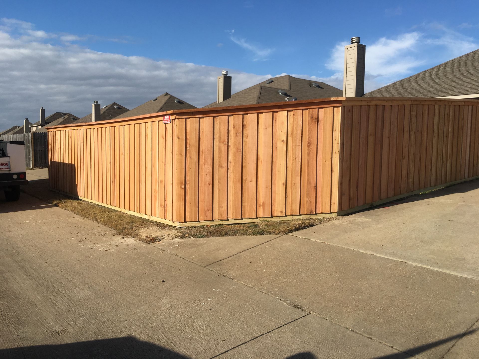 A wooden fence is sitting on the side of a road next to a house.