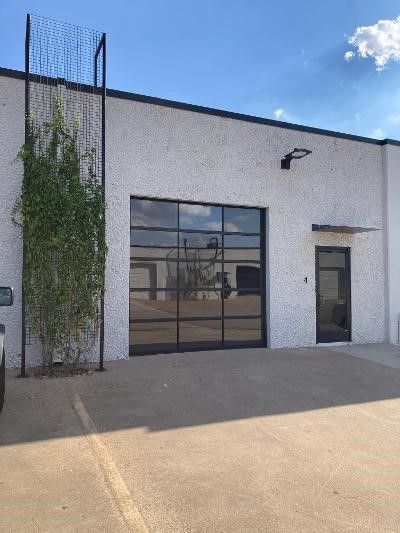 A white building with a large garage door and a car parked in front of it.