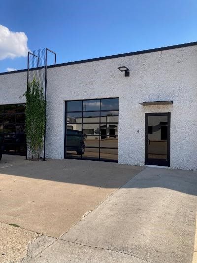 A white building with a large garage door and a black door.