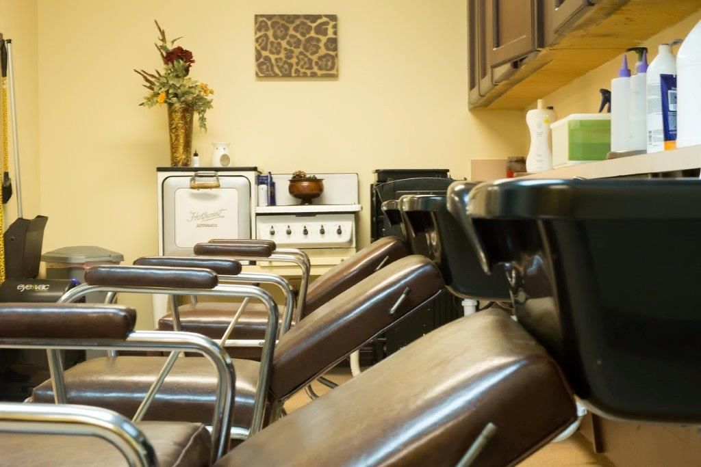 A row of chairs in a salon with a sink
