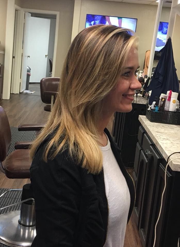 A woman is sitting in a chair in a hair salon.