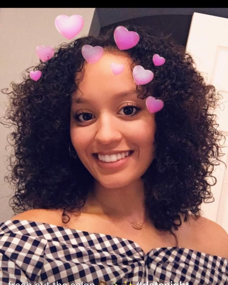A woman with curly hair is wearing a checkered off the shoulder top