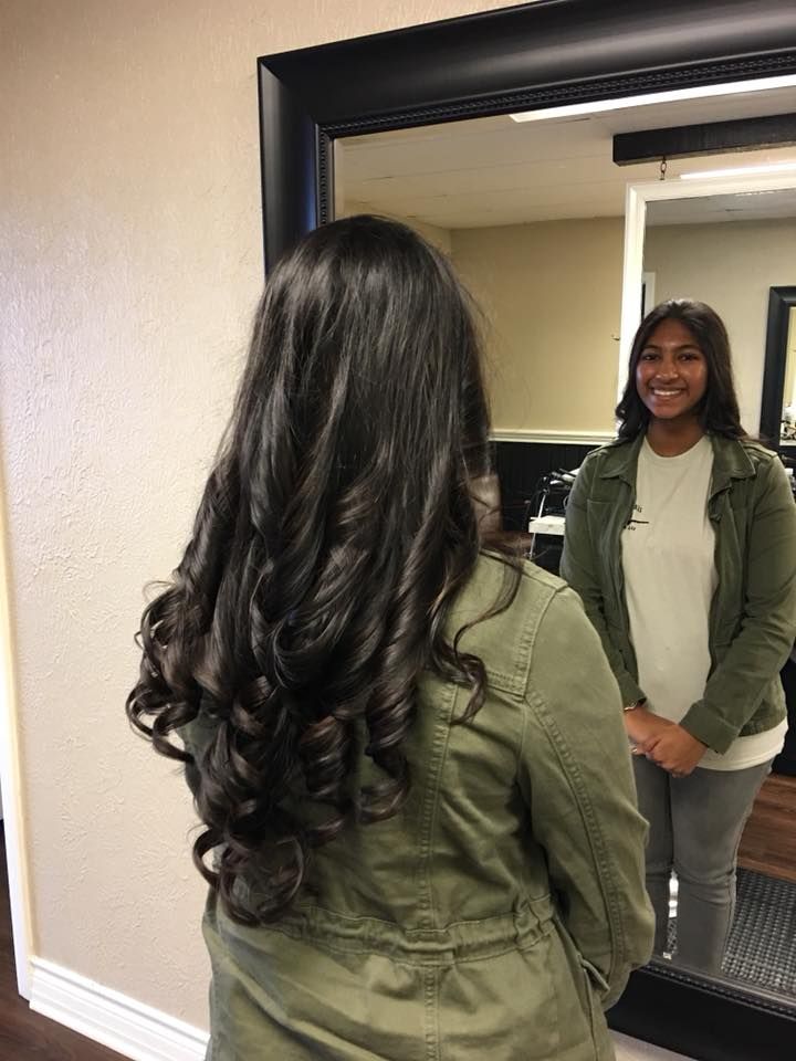 A woman with long hair is standing in front of a mirror.