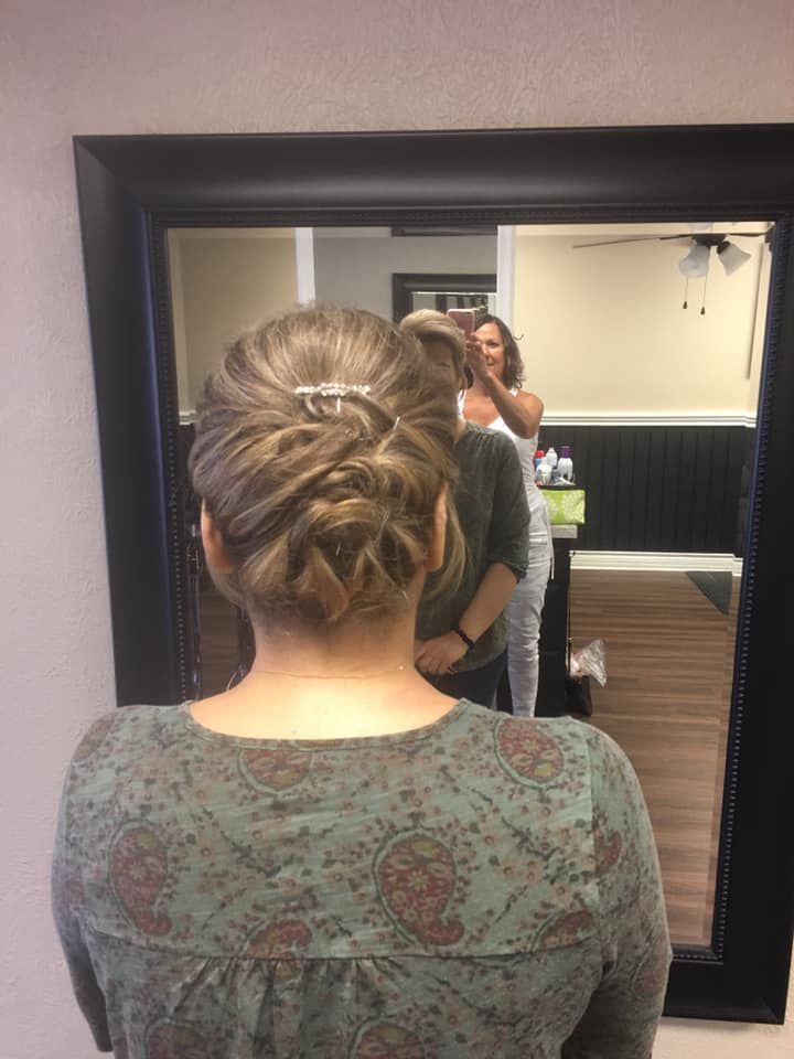 A woman is standing in front of a mirror with her hair in a bun.