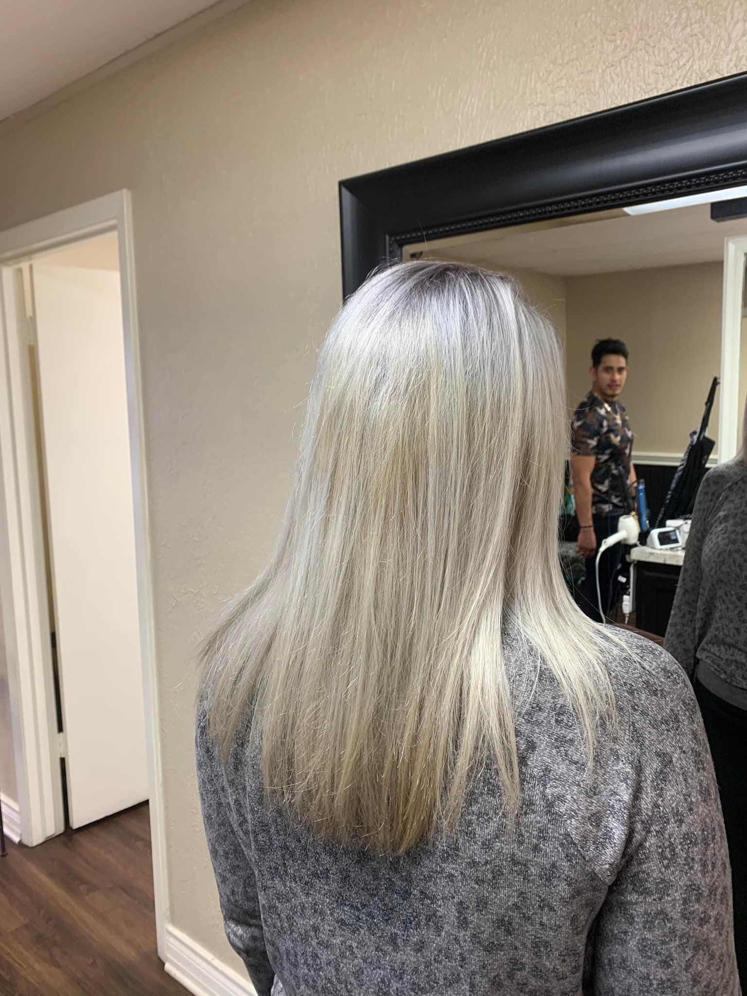 A woman is standing in front of a mirror looking at her hair.