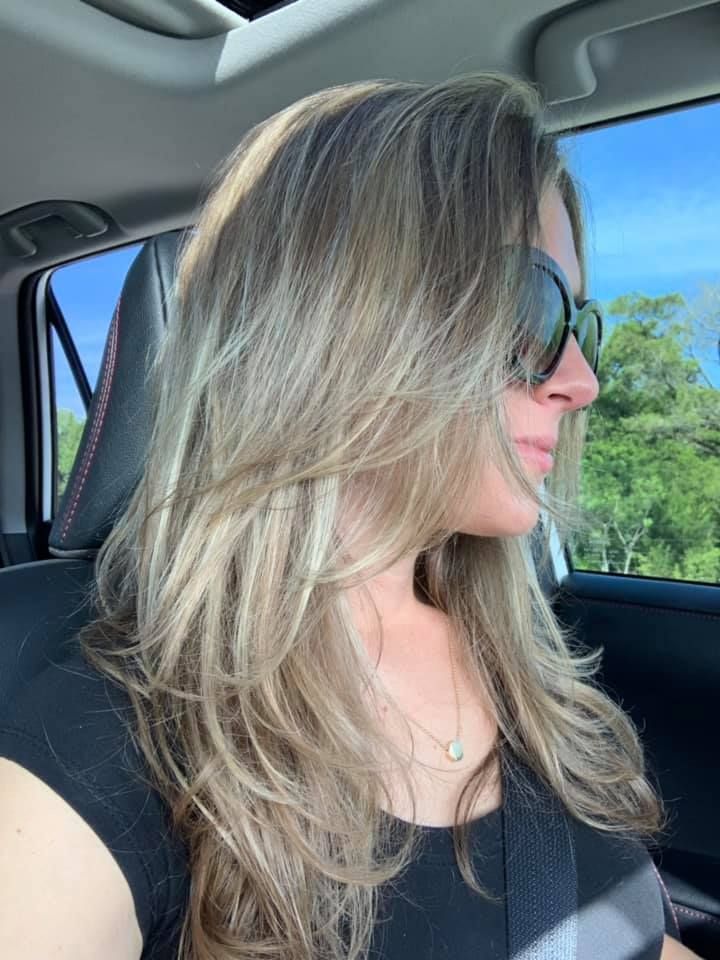 A woman wearing sunglasses is sitting in a car.