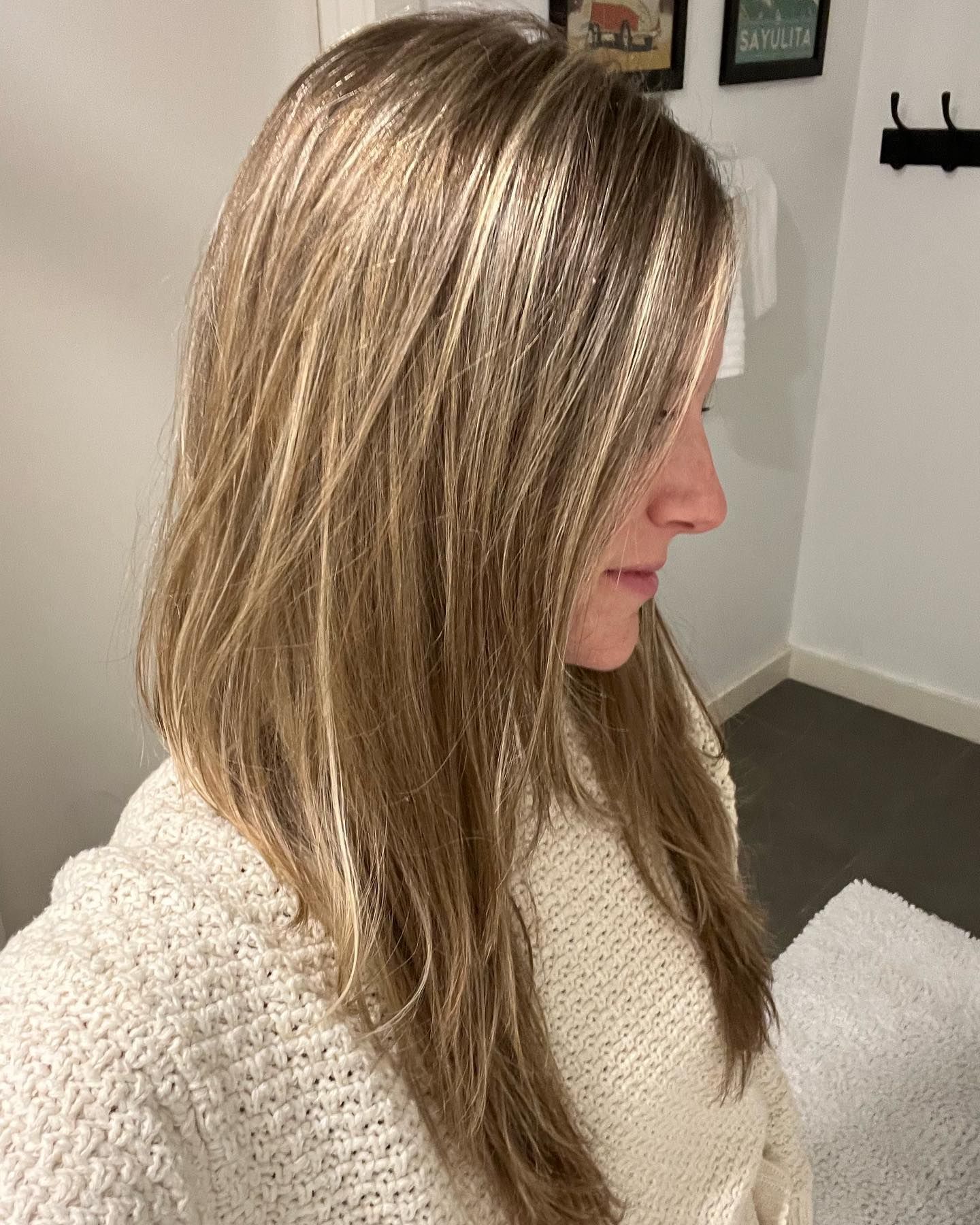 A woman with long blonde hair is wearing a white sweater.